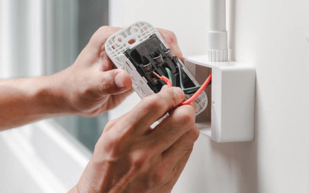 hands troubleshooting and repairing outlet in wall