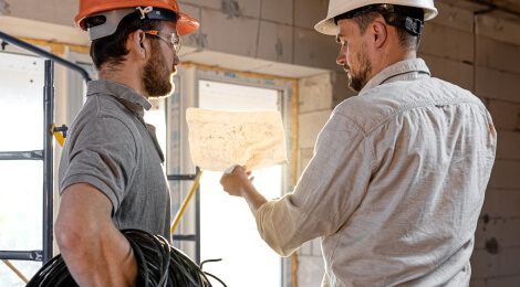 Construction workers talking about plans for wire install
