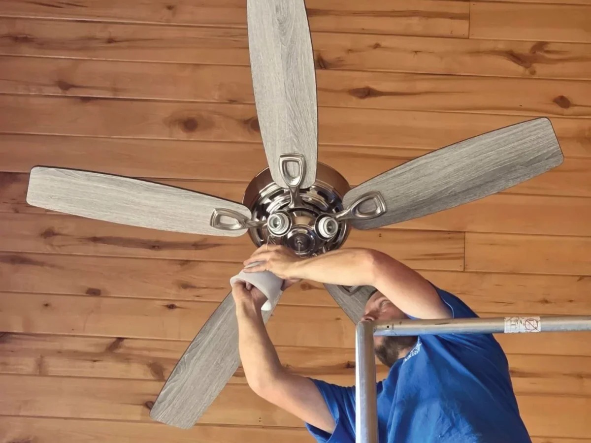 Local electrician installing ceiling fan and residential electrical fixtures